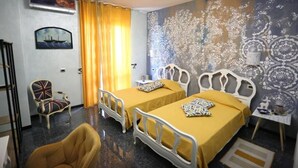 A hotel room with two single beds, a chair, a small table, and a decorative wall.