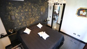 A hotel room with a bed, a chandelier, a mirror, and a decorative wall. - B&B L'Almancco: A Blend of Relaxation and Convenience (Motta Vigana)