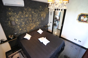 Una camera d'albergo con un letto, un lampadario, uno specchio e una parete decorata.