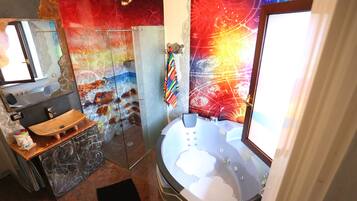 Ein Badezimmer mit Duschkabine aus Glas, Holzwaschtisch, Badewanne und farbenfrohem Wandbild.