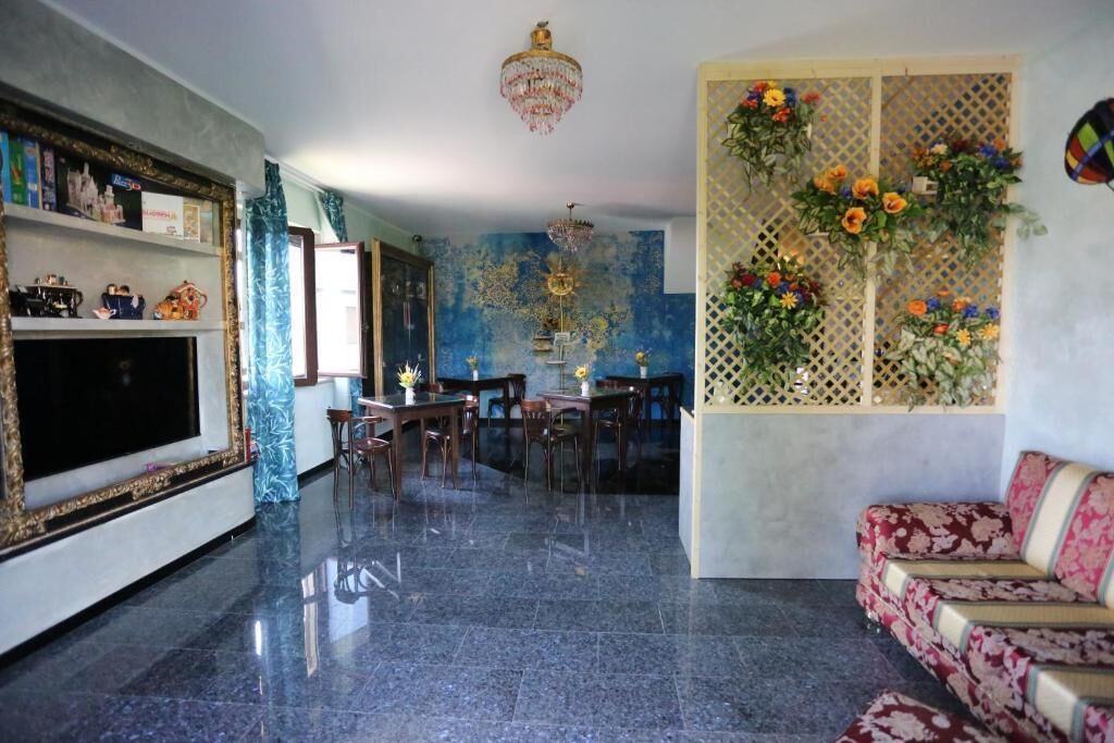 A spacious living area with a large flat-screen TV, a chandelier, a dining table with chairs, and a sofa.