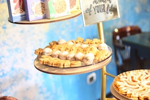 Een presentatie van diverse gebakjes op een glazen etagère, met een bordje erboven.