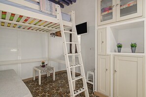A room with a bunk bed, a TV mounted on the wall, a small table with a plant, and a cabinet with potted plants. - Historic Center Studio – Terrace and Beach Nearby (Conil de la Frontera)