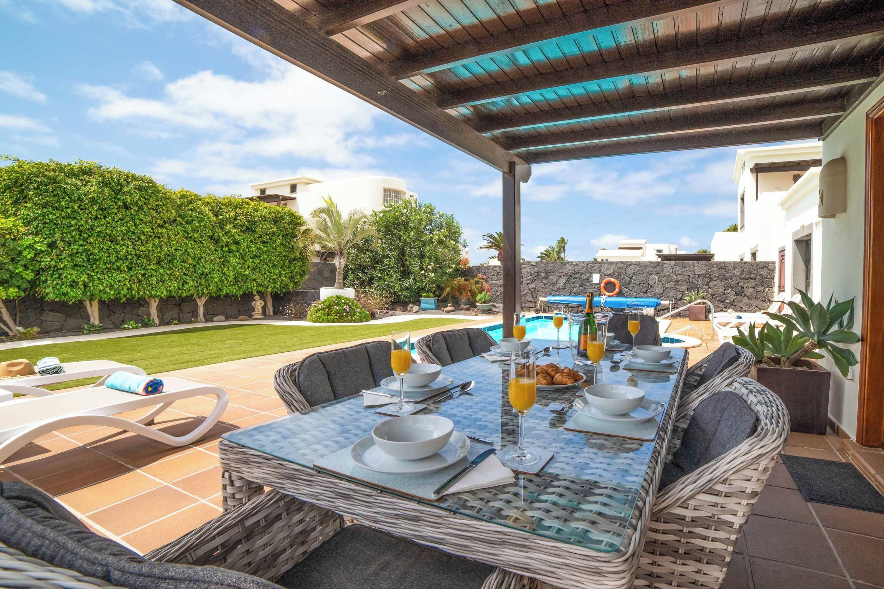 An outdoor dining area with a pool and a covered patio.