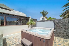 A hot tub with a wooden bench and stone tiles, surrounded by a stone wall and a clear blue sky. - Villa Aguamarina - Three Bedroom Villa, Sleeps 6 (Playa Blanca)