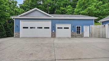 A two-story building with a garage, a small entry door, and a stone foundation.