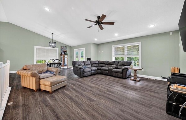A spacious living room with a sectional sofa, a recliner, and a ceiling fan.