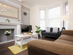 Een woonkamer met een open haard, een televisie, een bank en een eettafel.
