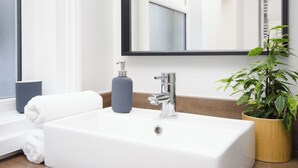 A bathroom with a white sink, a mirror, a towel, a soap dispenser, and a potted plant. - 46 Ashville Avenue (Scarborough)