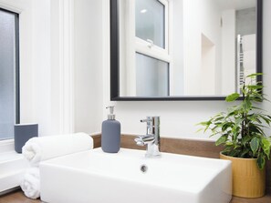 A bathroom with a white sink, a mirror, a towel, a soap dispenser, and a potted plant. - 46 Ashville Avenue (Scarborough)