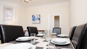 A dining area with a long table set for four, black leather chairs, white plates, clear glasses, and a pitcher. - 46 Ashville Avenue (Scarborough)