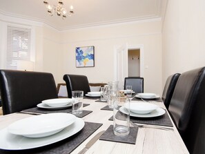 A dining area with a long table set for four, black leather chairs, white plates, clear glasses, and a pitcher. - 46 Ashville Avenue (Scarborough)