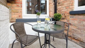 A small outdoor seating area with wicker chairs and a glass table, a potted plant, and a glass pitcher on the table. - 46 Ashville Avenue (Scarborough)