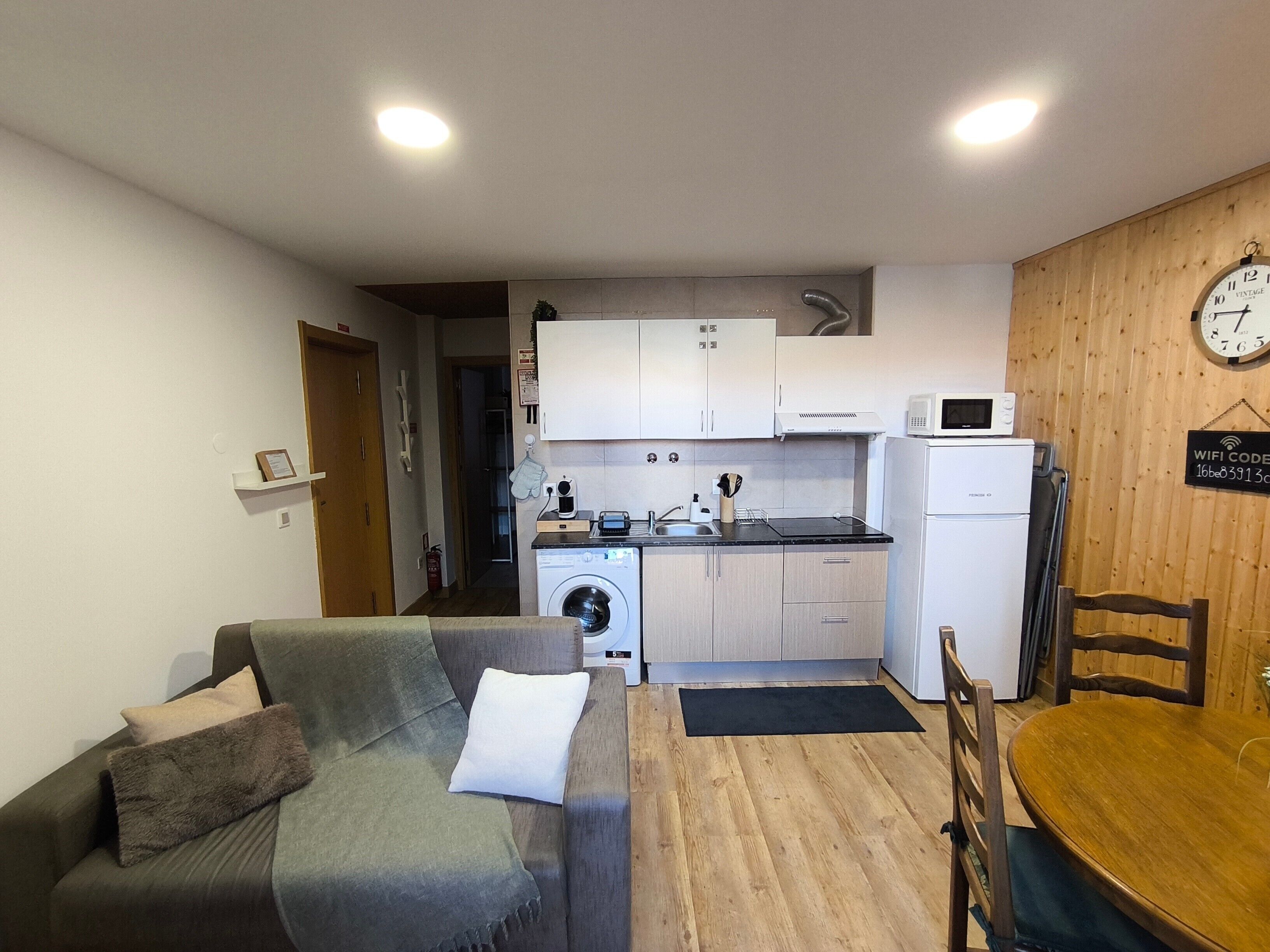 En kompakt bolig med tekøkken, sofa, spisebord og mikroovn.