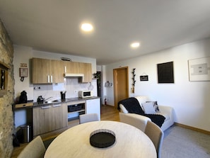 Un espacio habitable compacto con cocina, comedor y una pequeña zona de estar.