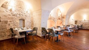 A restaurant with stone walls and wooden flooring, featuring tables and chairs arranged for dining. - Ve Hotels (Sanliurfa)