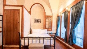 A bedroom with a four-poster bed, wooden flooring, a wooden door, and a window with curtains. - Ve Hotels (Sanliurfa)