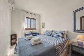 Une chambre à coucher avec un lit, des tables de chevet, une fenêtre et un miroir.