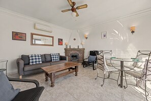 Un salon comprenant un canapé, une table basse, une cheminée et un coin repas avec des chaises et une table.