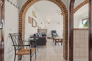 A room with a brick archway leading to a living area with a sofa, a table, and a chair.