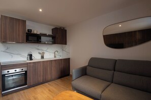 A modern kitchen with wooden cabinets, a built-in oven, and a marble backsplash. - K2 - Luxury Apartment: Terrace and View of the Slopes (Gérardmer)