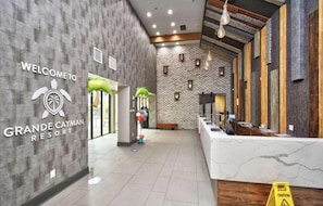 A reception area with a 'WELCOME TO GRANDE CAYMAN RESORT' sign, a reception desk, and a wall with a brick pattern. - Beach Daze. Ocean view studio. (Myrtle Beach)