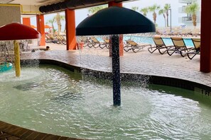 A pool area with water jets, lounge chairs, and a tiled deck. - Beach Daze. Ocean view studio. (Myrtle Beach)