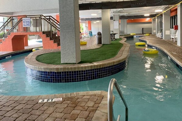 Una piscina interior amb vora de rajola, una petita zona enjardinada i una escala que condueix a un nivell superior.