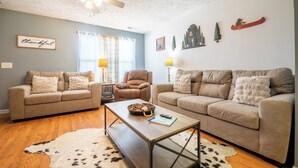 Ein Wohnzimmer mit zwei Sofas, einem Couchtisch, einem Deckenventilator und Wanddekorationen.