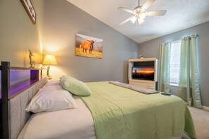 A bedroom with a bed, a television, a ceiling fan, and a painting on the wall. - Beary Cozy Condo, Hot Tub & Game Room, Dollywood (Sevierville)