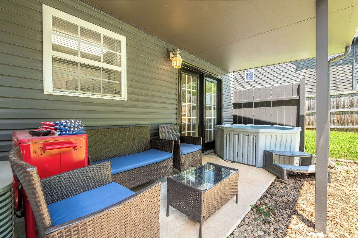A covered patio area with outdoor furniture, a hot tub, and a red suitcase.