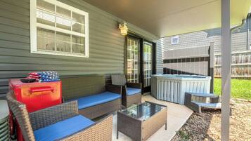 A covered patio area with outdoor furniture, a hot tub, and a red suitcase.