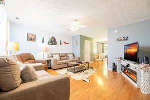 A living room with a sofa, a coffee table, a fireplace, and a television. - Beary Cozy Condo, Hot Tub & Game Room, Dollywood (Sevierville)