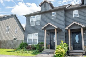 A two-story house with a dark gray exterior, a front porch with steps, and a black front door. - Beary Cozy Condo, Hot Tub & Game Room, Dollywood (Sevierville)