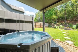 A hot tub in a backyard with a wooden fence, a grassy lawn, and a wooden deck. - Beary Cozy Condo, Hot Tub & Game Room, Dollywood (Sevierville)