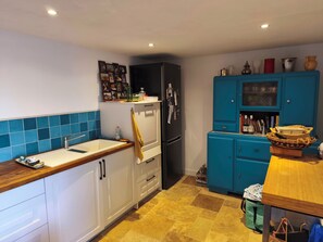 Eine Küche mit weißen Schränken, einem schwarzen Kühlschrank, einer blauen Fliesenrückwand und einer Holzarbeitsplatte.