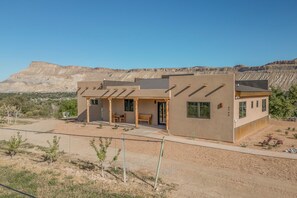 A modern two-story house with a patio and a view of a desert landscape. - Peach Valley Vista - Sunset Views, Orchards & Wine Country Escape (Palisade)