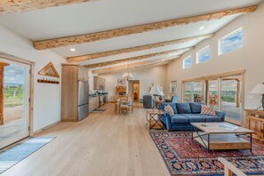 A spacious living area with a sofa, coffee table, and a view of the outdoors. - Peach Valley Vista - Sunset Views, Orchards & Wine Country Escape (Palisade)