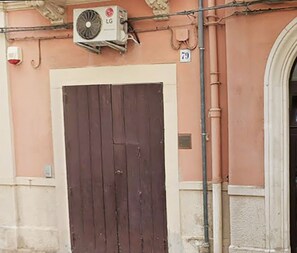 Ein Gebäude mit einer geschlossenen, dunkelholznen Tür, einer Klimaanlage und einem Schild mit der Nummer 79.