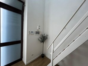 A staircase with a handrail, a wall-mounted intercom system, and a potted plant. - Bari Love Loft - Historic Center, Beach, Train Station, and Airport Just a Short Walk Away (Bari)