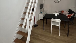 A staircase leading to a loft area with a dining table and chairs, a clock on the wall, and a small side table with a vase. - Bari Love Loft - Historic Center, Beach, Train Station, and Airport Just a Short Walk Away (Bari)