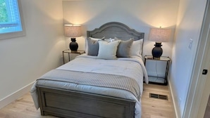 Een slaapkamer met een bed, twee nachtkastjes, een raam en een deur.