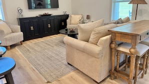 Een woonkamer met een bank, een salontafel, een televisie en een eettafel.