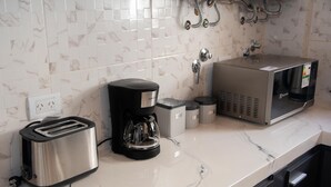 A kitchen with a toaster, coffee maker, microwave, and trash bins on a marble countertop. - A guesthouse with an excellent location, a gym, and a game room (Buenos Aires)