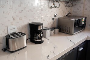 Eine Küche mit Toaster, Kaffeemaschine, Mikrowelle und Mülleimern auf einer Marmorarbeitsplatte.