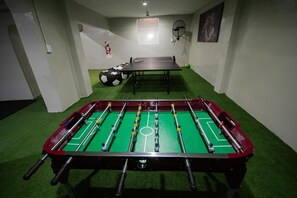 A foosball table in a room with green artificial turf, a ping pong table, and a soccer ball. - A guesthouse with an excellent location, a gym, and a game room (Buenos Aires)