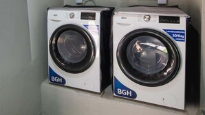 Dos lavadoras de carga frontal con la etiqueta BGH en un lavadero con piso verde artificial.