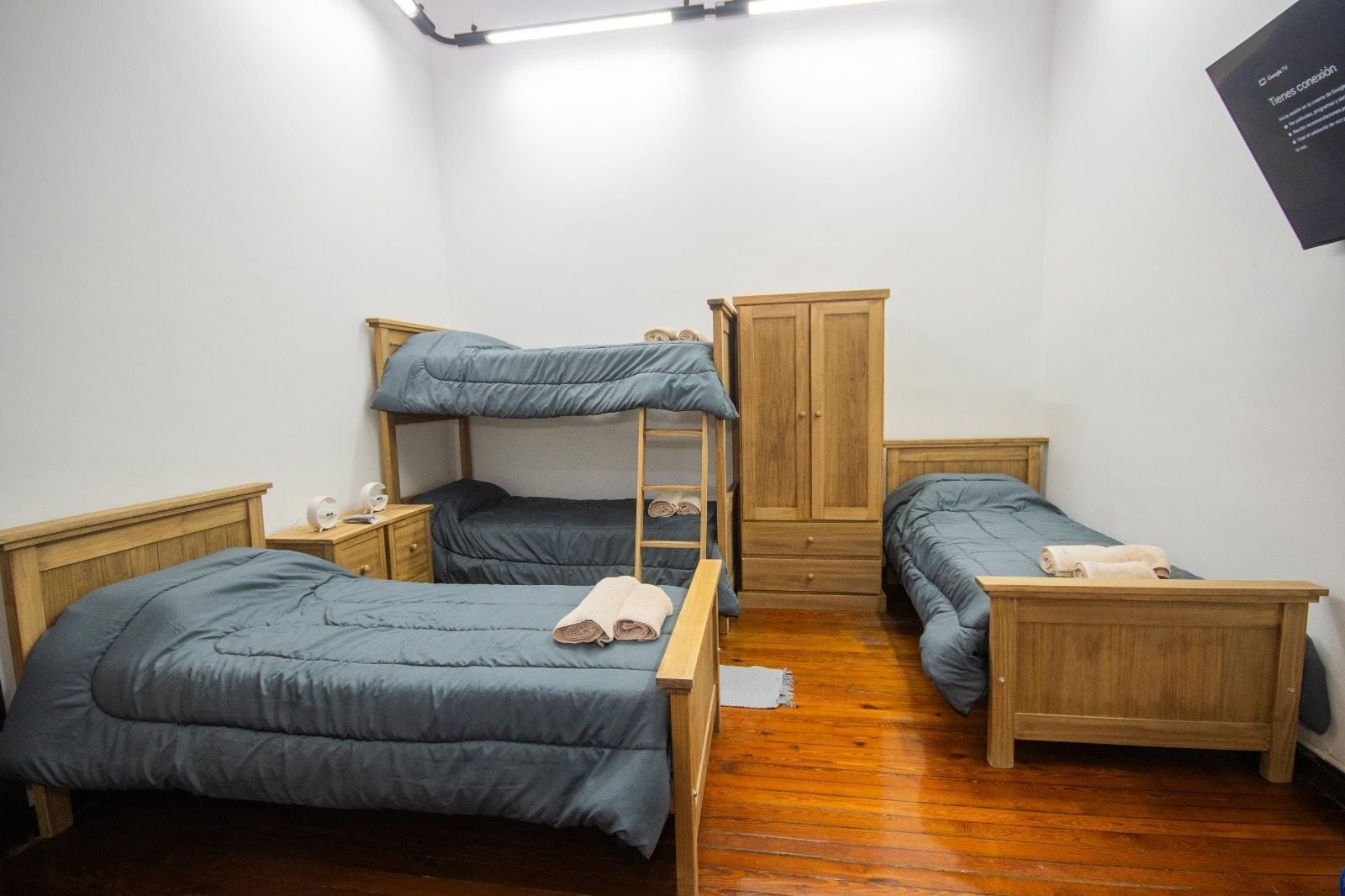 A room with bunk beds, a wooden wardrobe, and a bedside table with a lamp.