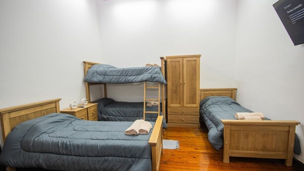 Una habitación con literas, un armario de madera y una mesita de noche con lámpara.