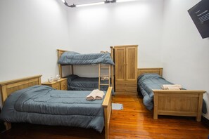 A room with bunk beds, a wooden wardrobe, and a bedside table with a lamp. - A guesthouse with an excellent location, a gym, and a game room (Buenos Aires)
